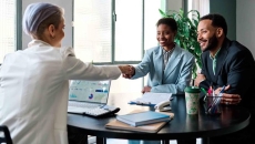 Businessperson shaking hands with a client while another person watches