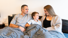 A family of three featuring a mother wearing the AeviceMD wearable stethoscope