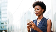 Person standing on a city block looking at their phone
