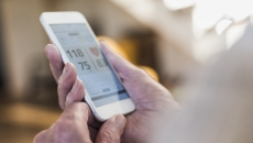 A person holding a phone showing a blood pressure reading