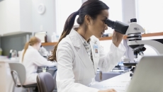 Healthcare professional looking into a microscope