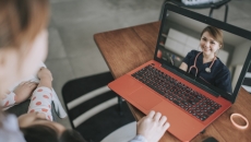 Person sitting down with a computer in front of them with a healthcare provider on the screen