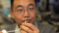 A researcher holding a small-scale surgical robot