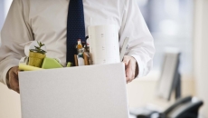 A man leaving an office carrying a box of his belongings.