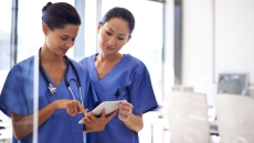 Two nurses using a tablet to review medical records.