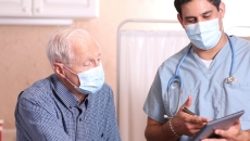 A medical professional with a tablet consults with patient