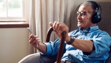 An older man using a smartphone and wearing headphones