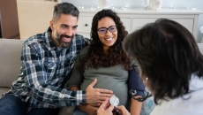 A doctor visits a pregnant patient and partner at home