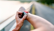 A close up photo of a person using a wearable while on a running trail