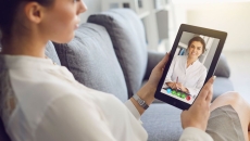Person sitting on their couch speaking to a healthcare professional on a tablet
