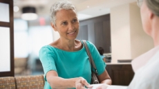 A person handing an insurance card to a front desk worker at a medical office