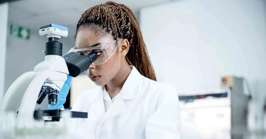 Scientist in a lab looking at a microscope