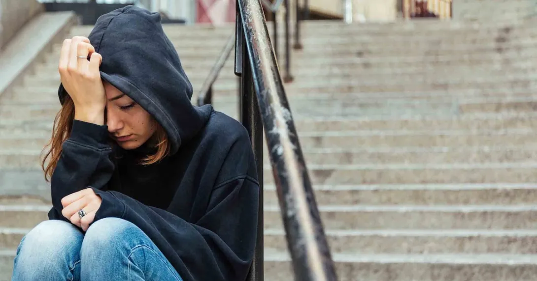 Person sitting on steps with their head in their hand