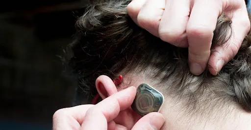 A person pulling back their hair to place the sensor