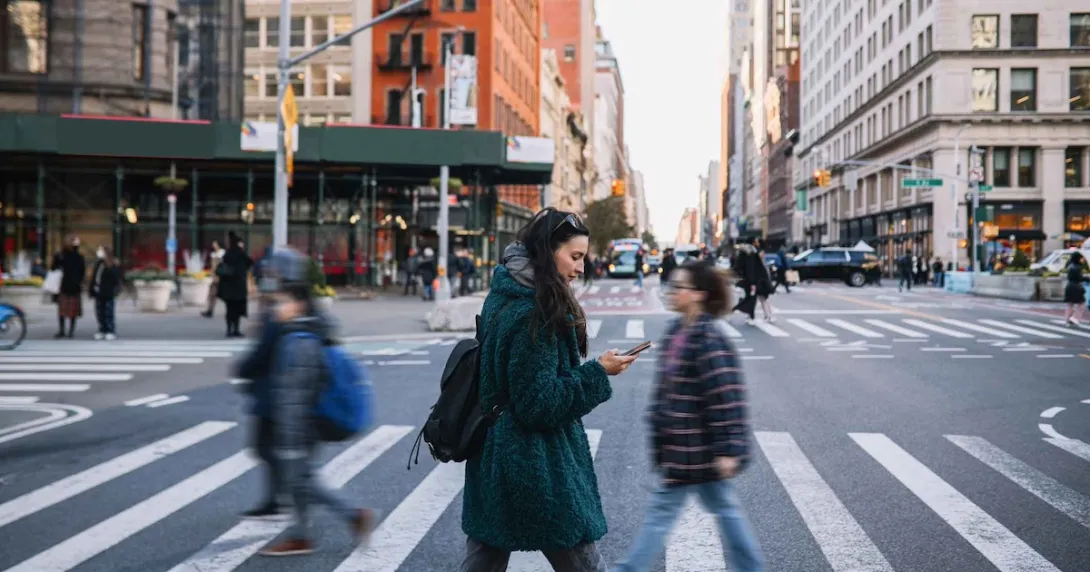 People walking across a crosswalk in the streets of a large city