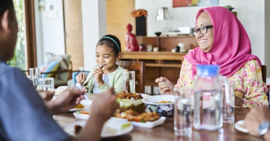 People sitting around a dining room table with food on it