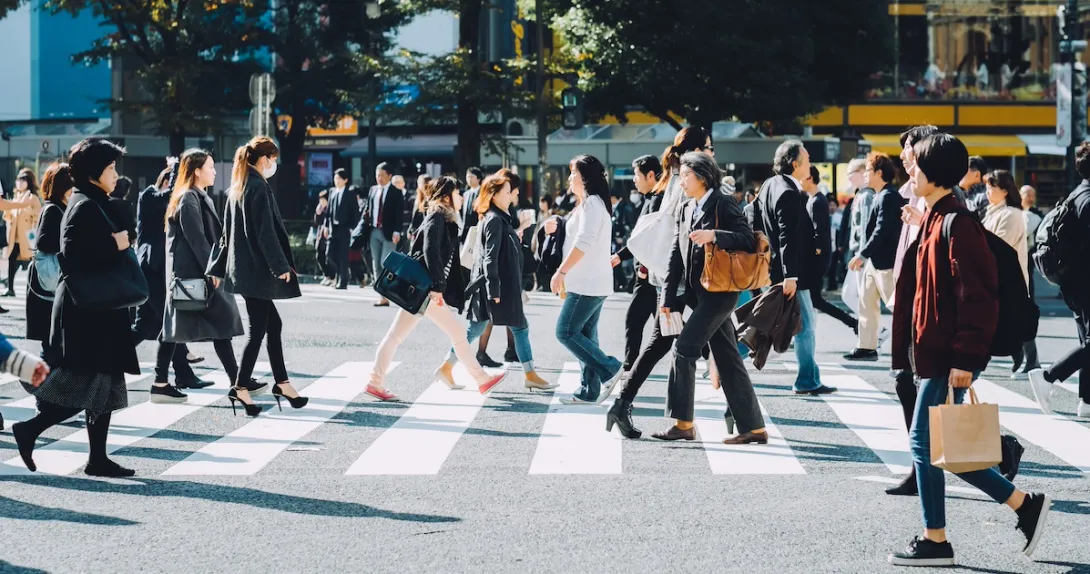 Many individuals walking on a city crosswalk
