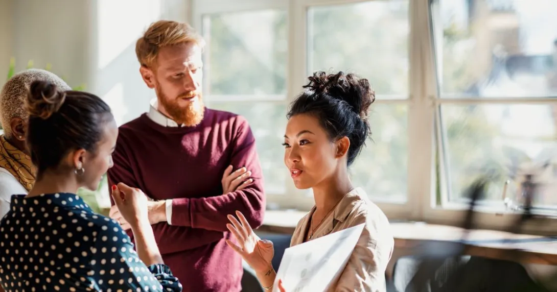 Person in maroon sweater talks with people wearing beige, polka dots