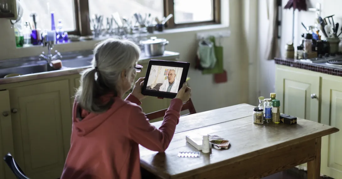 Person sitting at a table looking at a tablet