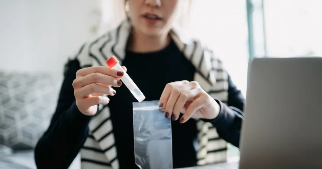 Person in their home sitting in front of a computer putting a test in a bag