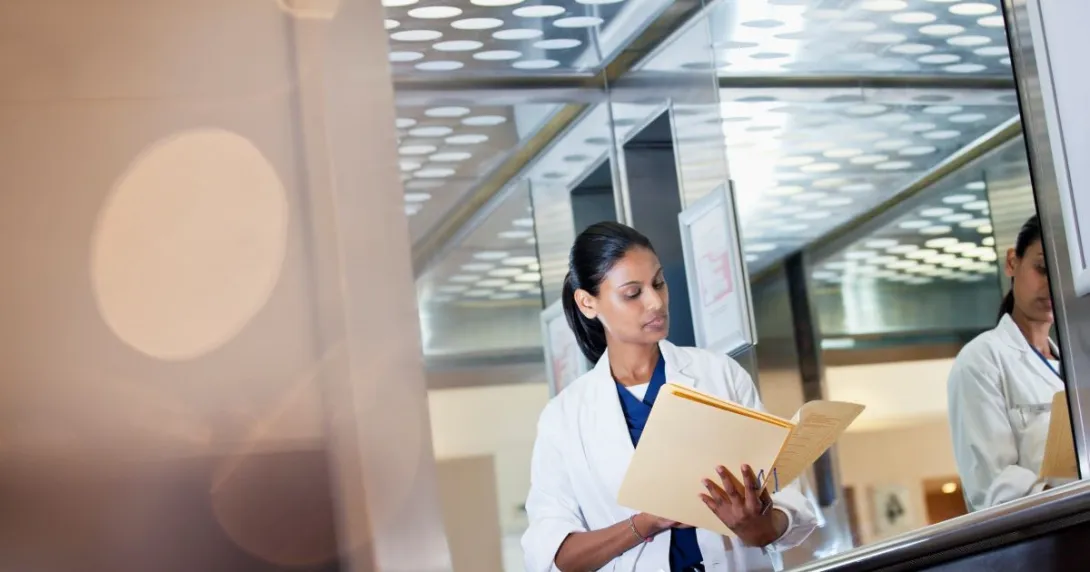 Person in lab coat looking down at file