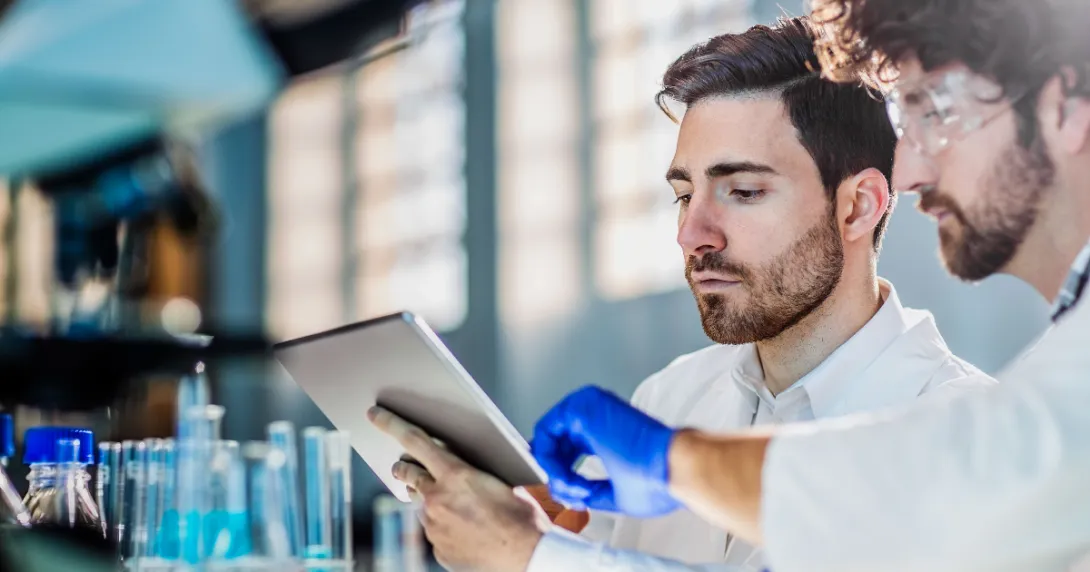 Two workers in a laboratory looking at a tablet