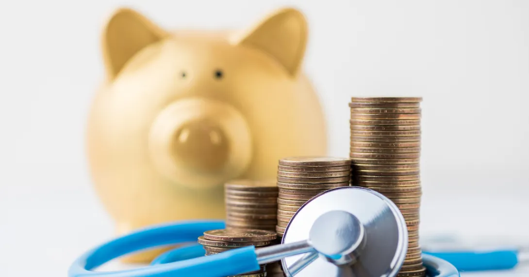 Piggy bank next to coins and a stethoscope