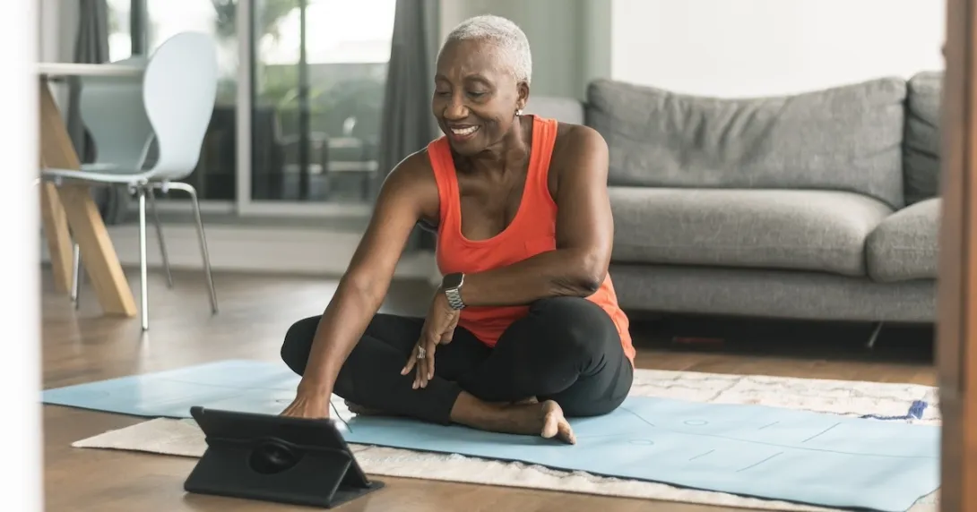 Person sitting on exercise mat interacting using a tablet