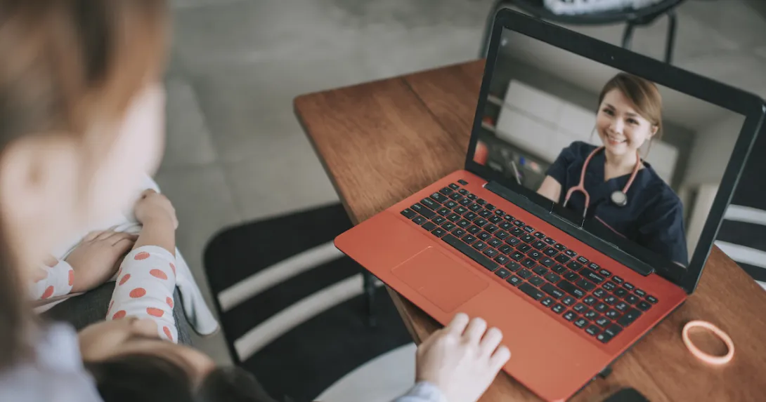 Person sitting down with a computer in front of them with a healthcare provider on the screen