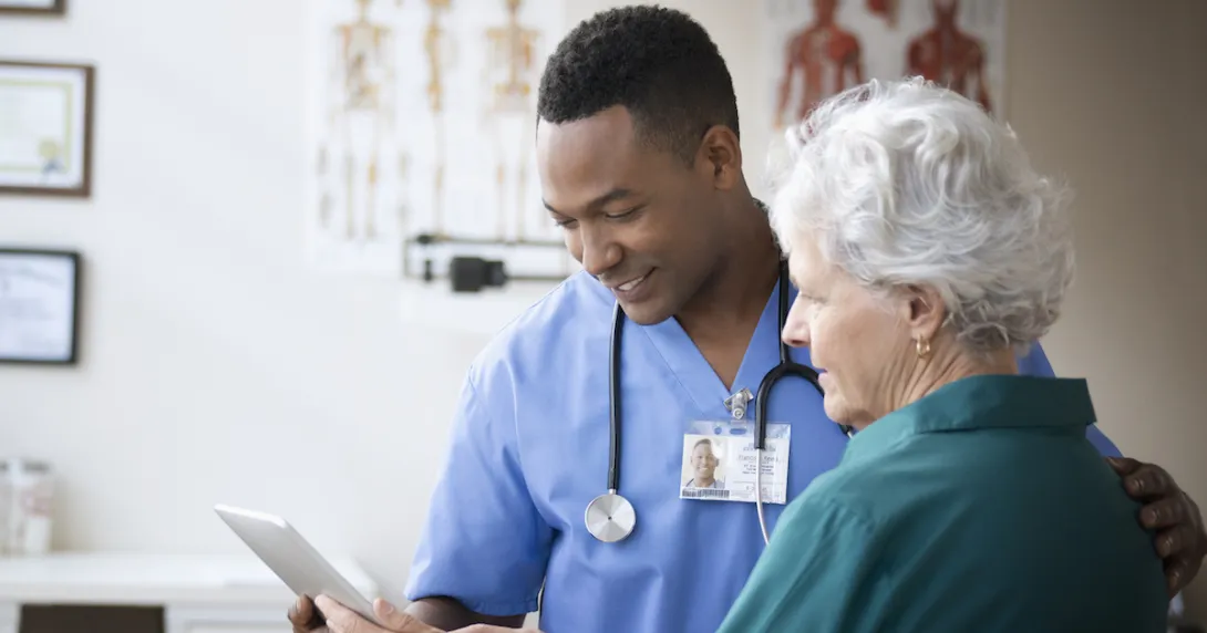 A doctor looking at a tablet with a patient.