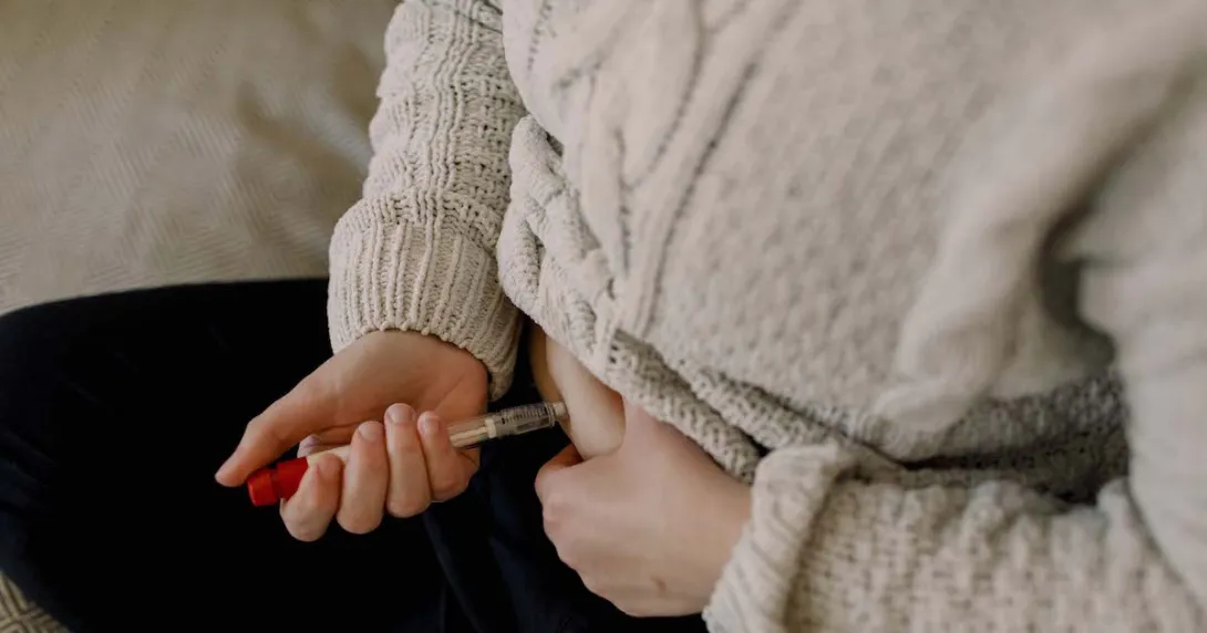 A close up of a person injecting fertility medication into their abdomen