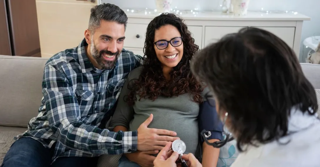 A doctor visits a pregnant patient and partner at home