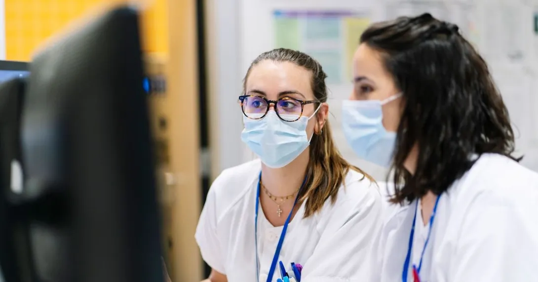 Two providers wearing masks working on a computer