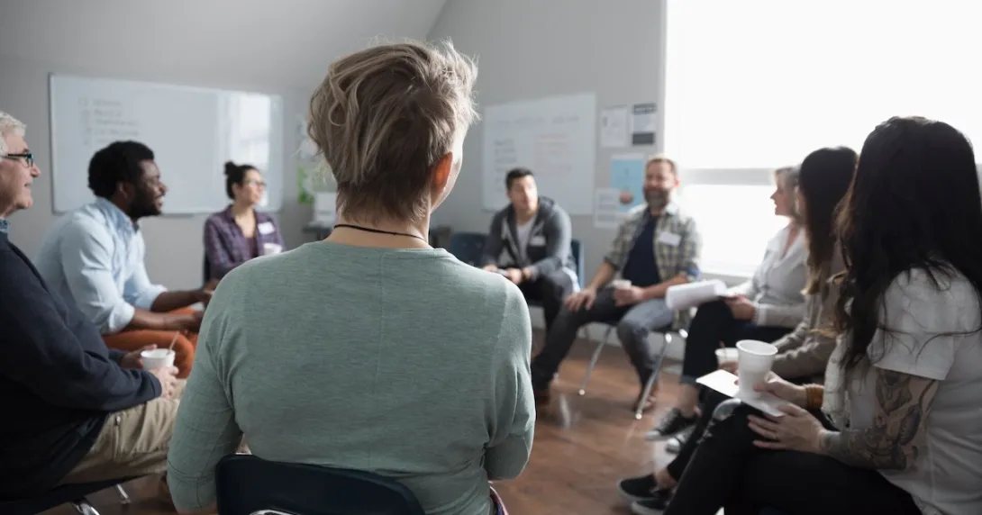 Group of people sitting in a room in a circle