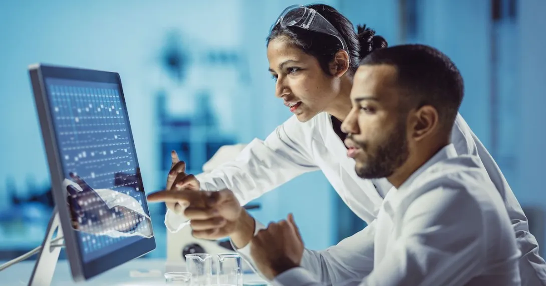 Two healthcare professionals at a desk while looking at a computer screen