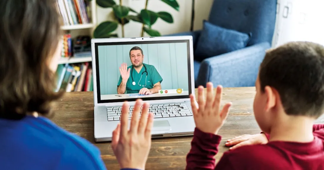 Two people waving at a healthcare provider on a computer