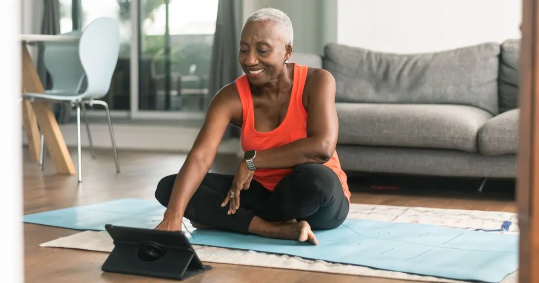 A woman takes an online exercise class on a tablet