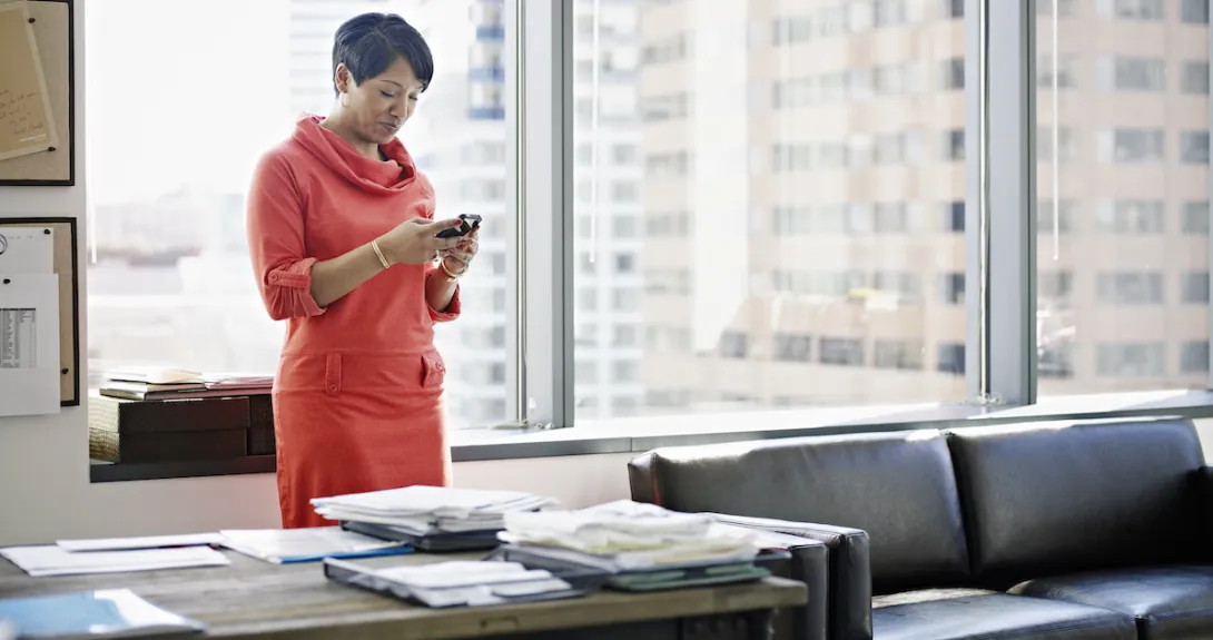 A person standing at desk looking at a smartphone