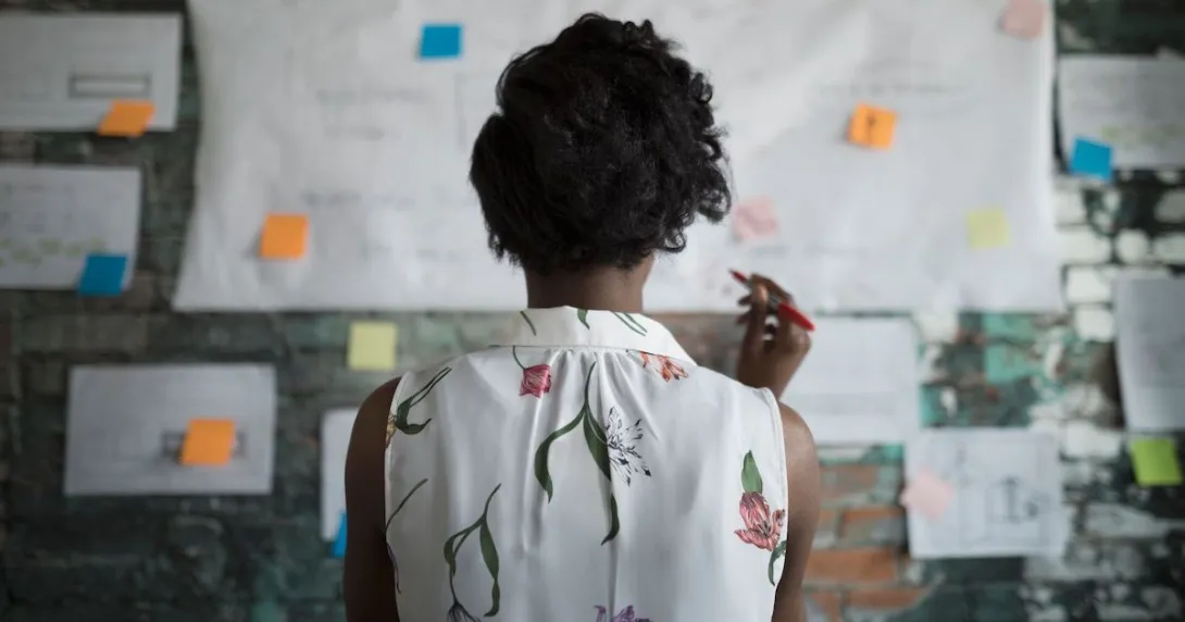 A woman at work standing in front of a wall with papers and planning documents